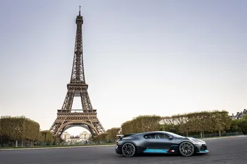 Vista frontal y lateral del Bugatti Divo junto a la Torre Eiffel, destacando su diseño aerodinámico.