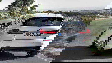 BMW Serie 1 en carretera, vista lateral y trasera, destacando su dinámica silueta.
