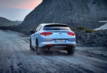 Vista trasera del Alfa Romeo Stelvio en un entorno montañoso, destacando sus líneas elegantes.