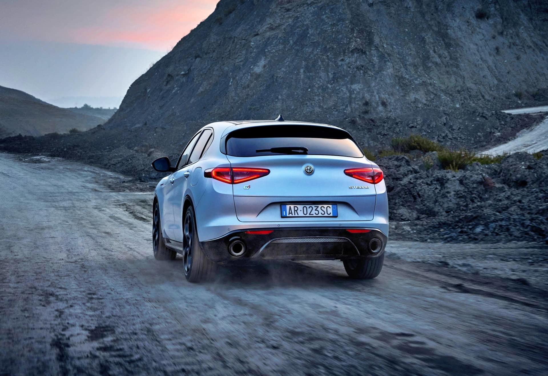Vista trasera del Alfa Romeo Stelvio en un entorno montañoso, destacando sus líneas elegantes.