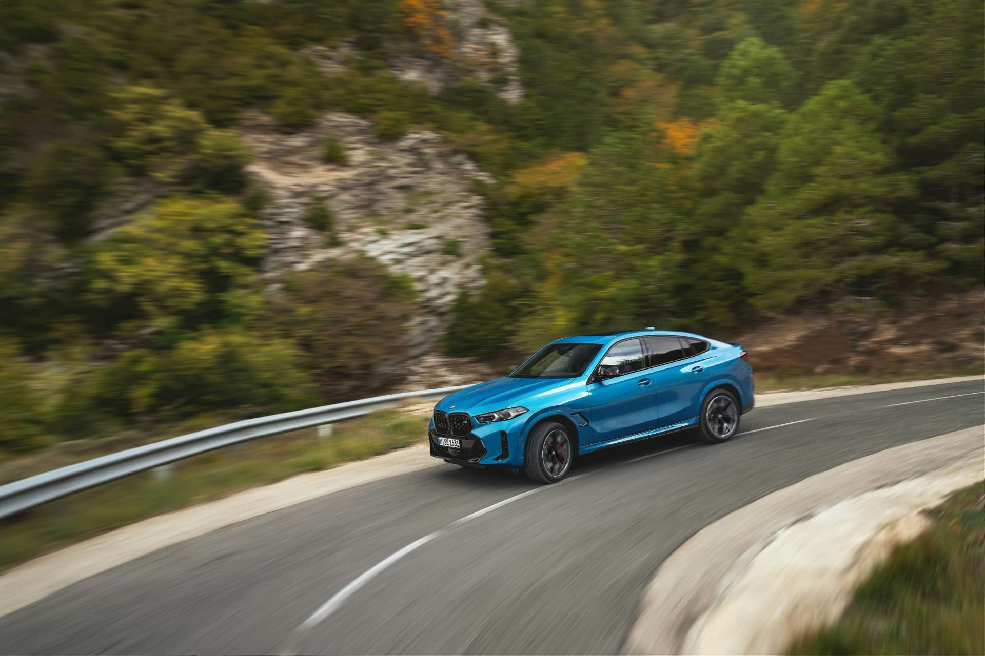 Vista lateral del BMW X6 en una carretera de montaña, destacando su diseño fluído.