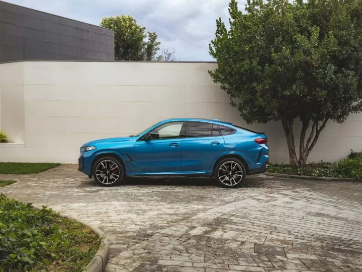 BMW X6 azul en una vista lateral dinámica, realzando su distintivo diseño coupé.