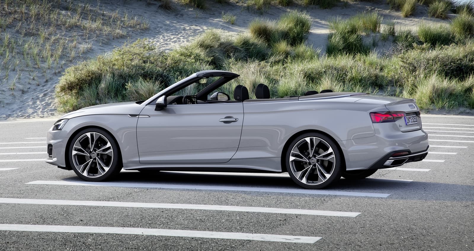 Vista lateral del Audi A5 Cabrio en movimiento, resaltando su diseño elegante.