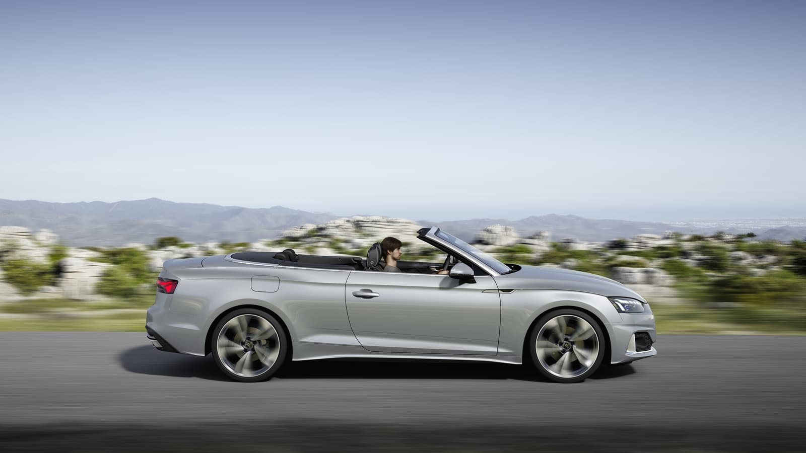 Vista dinámica del Audi A5 Cabriolet con capota baja, reflejando elegancia y deportividad.