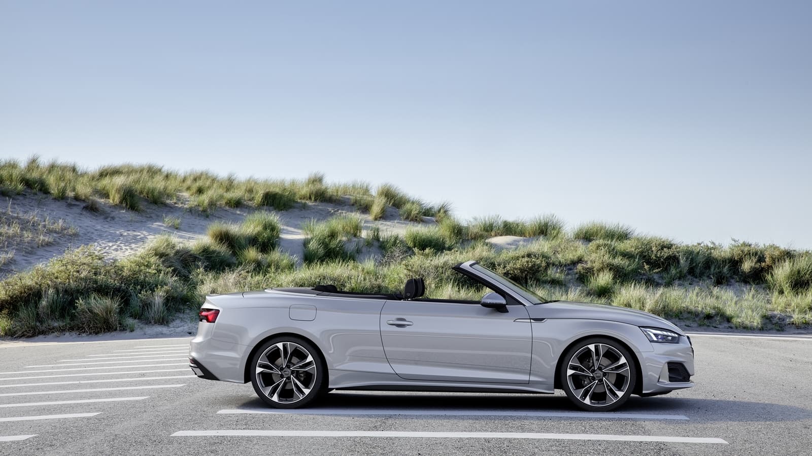 Vista lateral del Audi A5 Cabriolet con capota baja cerca de la playa.