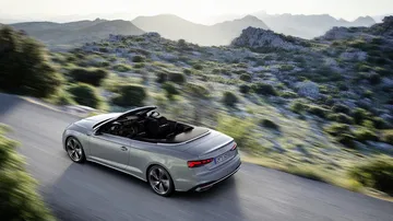 Vista dinámica lateral del Audi A5 Cabriolet con el techo plegado.