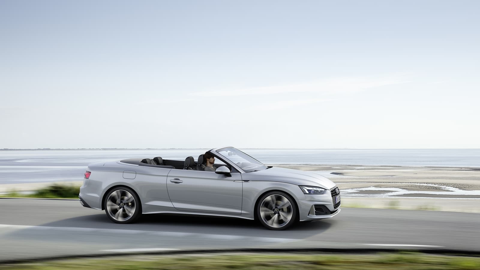 Elegante perfil lateral del Audi A5 Cabriolet con el techo replegado.