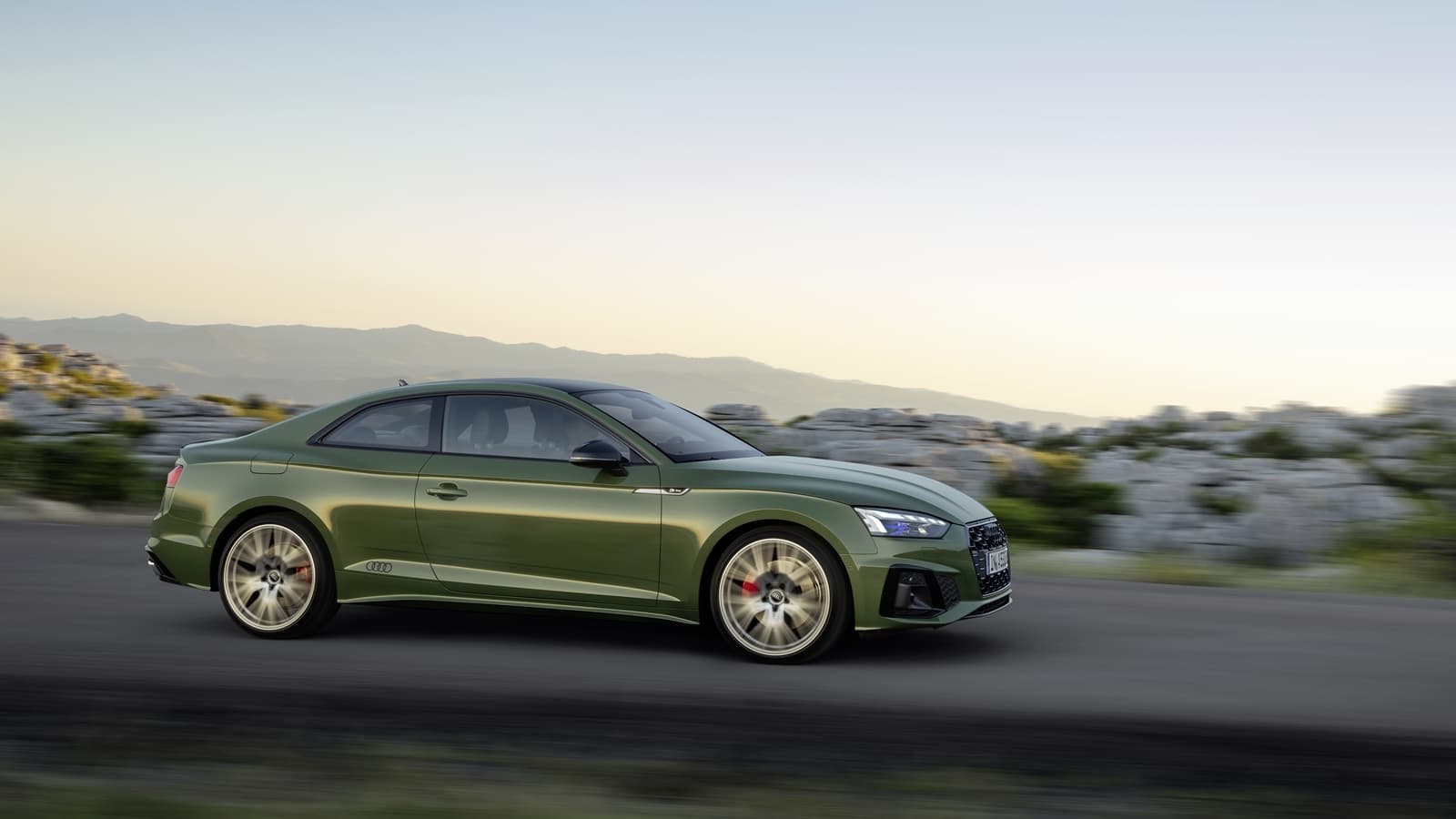 Vista en movimiento lateral del Audi A5 Coupé, resaltando su diseño aerodinámico.