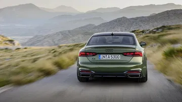 Vista trasera y lateral del Audi A5 Coupé en movimiento, destacando su diseño aerodinámico.