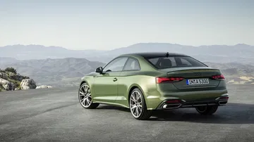 Vista dinámica del Audi A5 Coupé con paisaje montañoso de fondo.