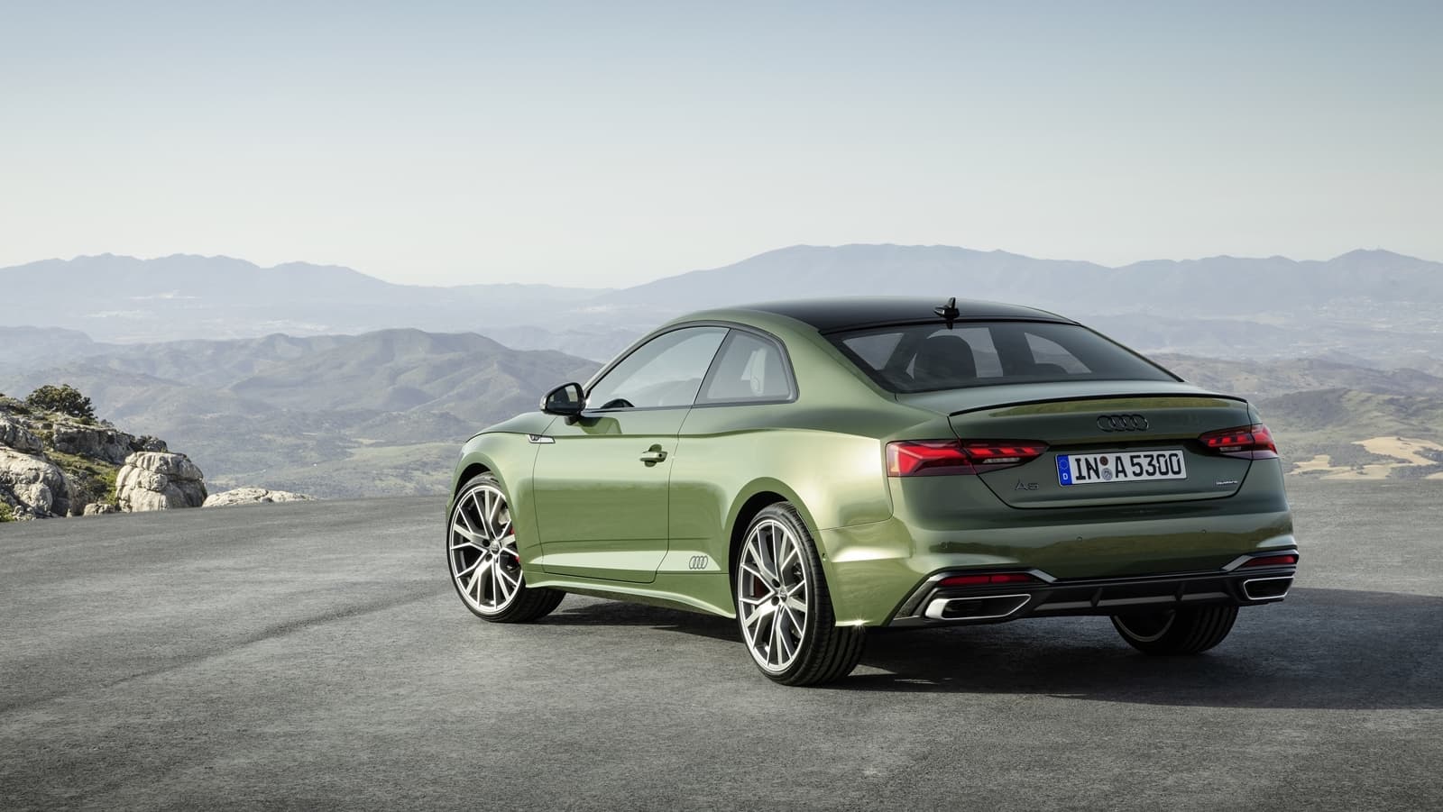 Vista dinámica del Audi A5 Coupé con paisaje montañoso de fondo.