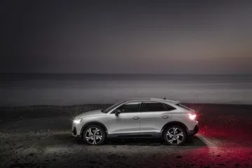 Vista lateral del Audi Q3 Sportback iluminado con un fondo nocturno.
