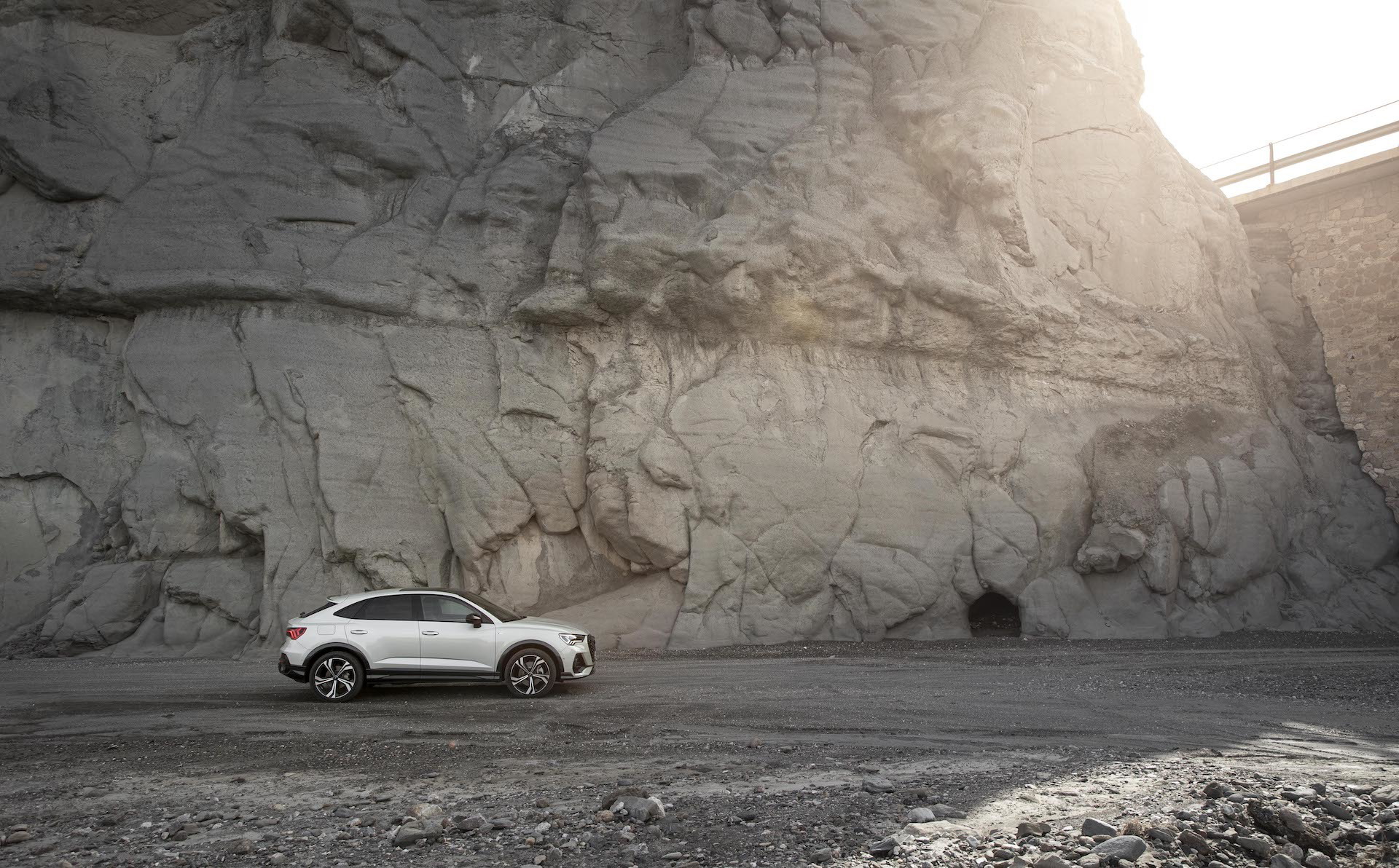 Vista lateral del Audi Q3 Sportback contrastando con una pared rocosa.