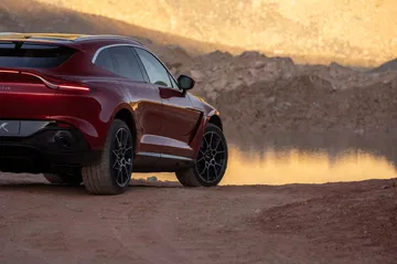 Vista trasera y lateral del Aston Martin DBX en movimiento, destacando su diseño deportivo.