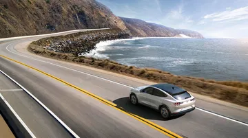 Vista dinámica del Ford Mustang Mach-E en una carretera costera.