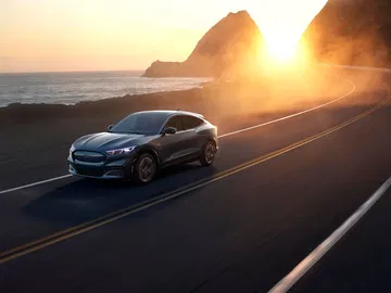 Ford Mustang Mach-E circulando en carretera al atardecer.