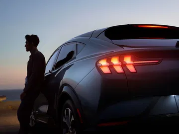 Perfil trasero del Mustang Mach-E al atardecer, destaca la iluminación LED característica.