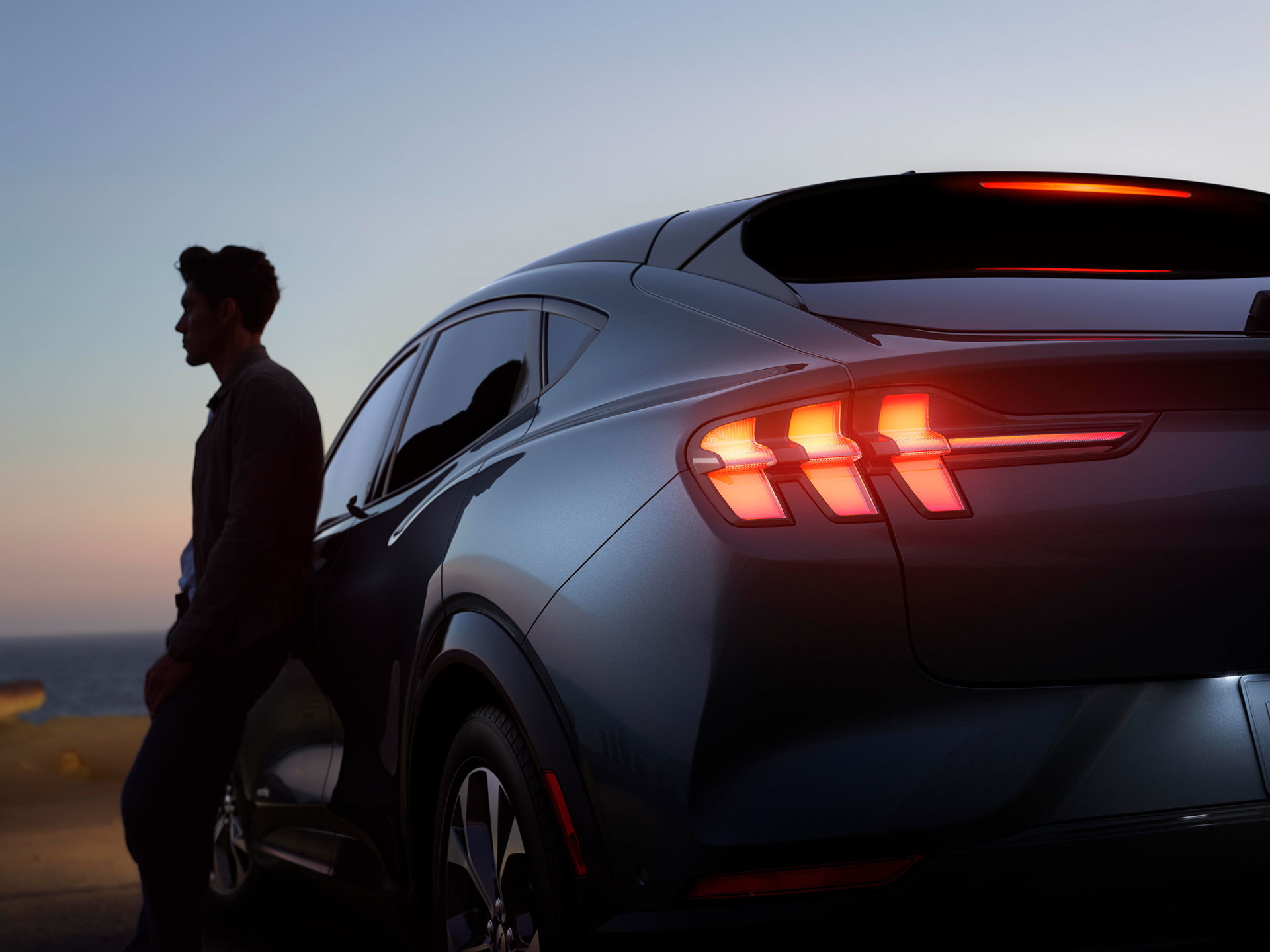 Perfil trasero del Mustang Mach-E al atardecer, destaca la iluminación LED característica.