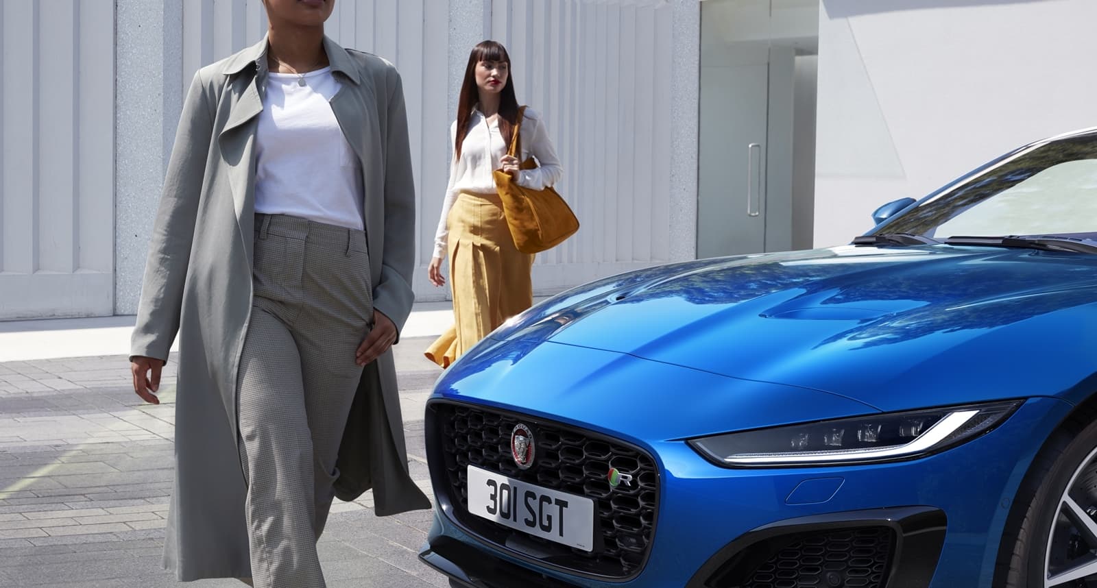 Vista delantera del Jaguar F-Type acompañado por dos modelos.