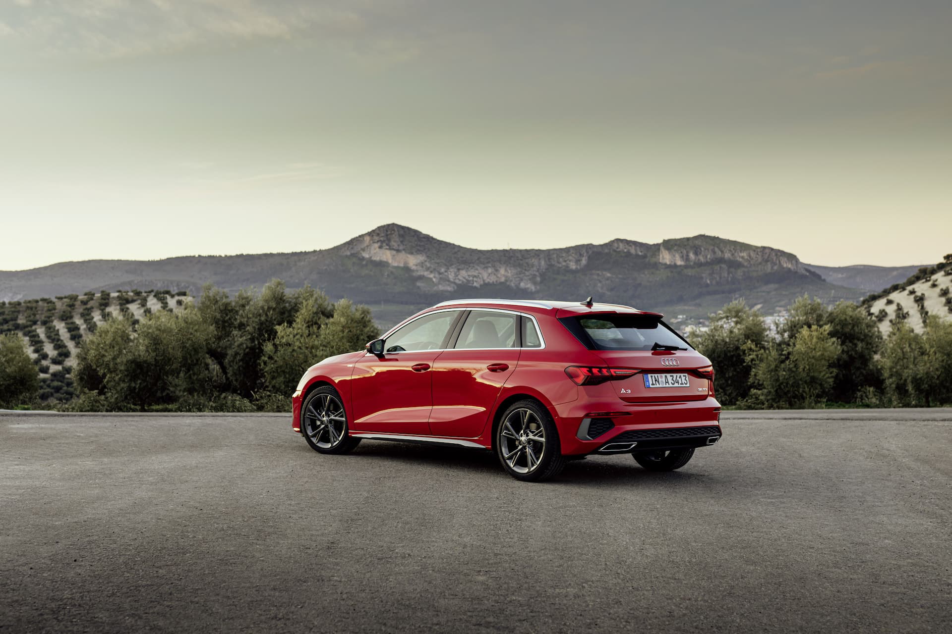 Audi A3 Sportback 2020 en rojo tango, vista trasera y lateral en carretera.