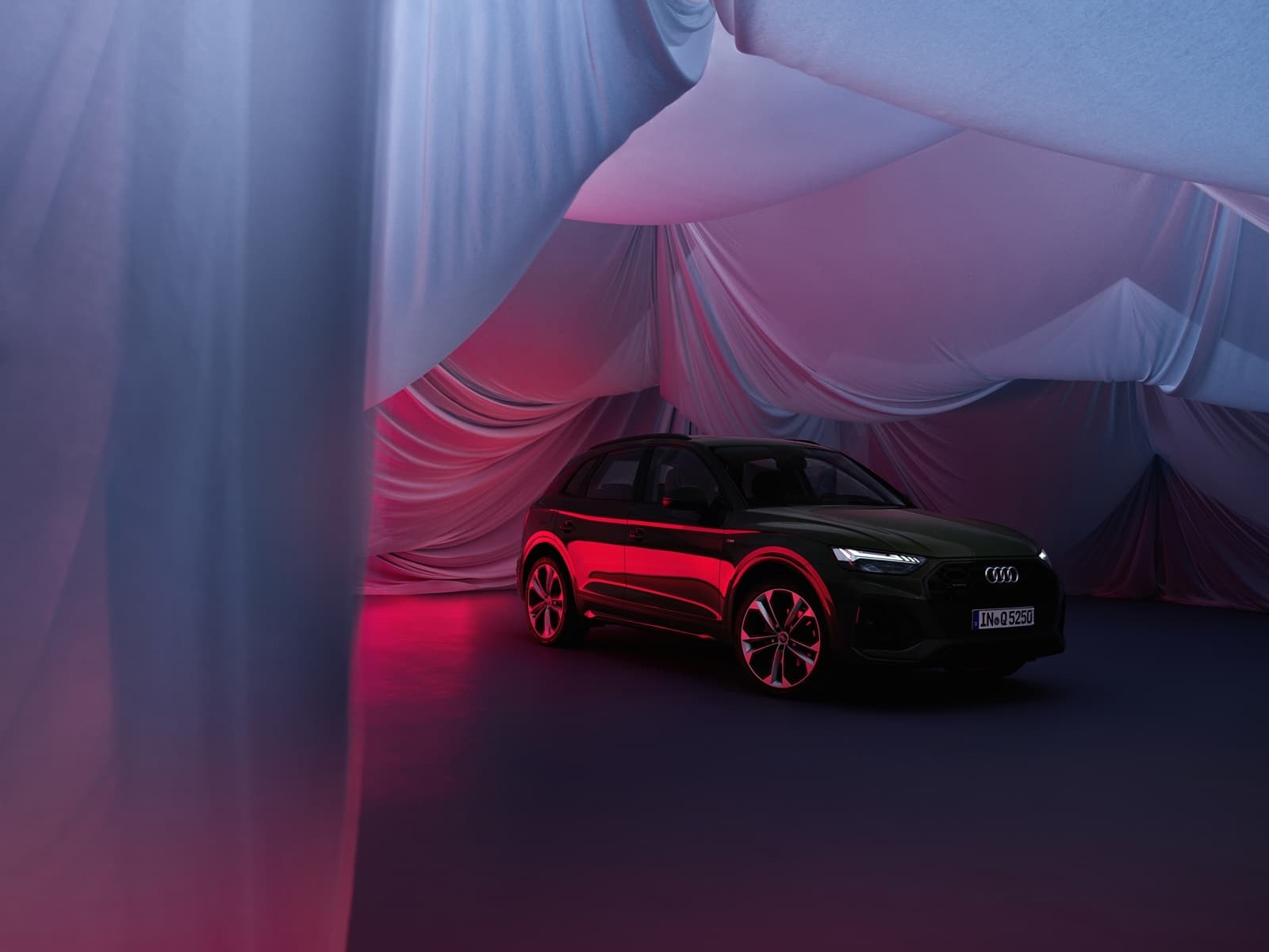 Audi Q5 apenas visible, cubierto con una lona roja sugestiva.