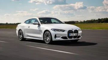 Vista dinámica del BMW Serie 4 Coupé en blanco, con enfoque en la parrilla y llantas.