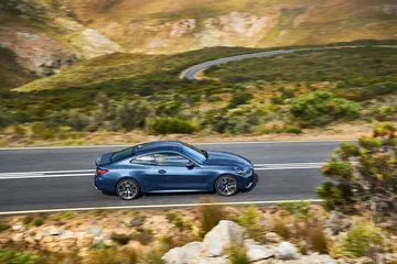 Vista lateral del BMW Serie 4 en carretera de montaña, destacando su dinámica de conducción.