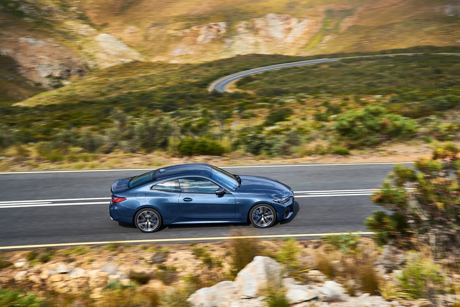 Vista lateral del BMW Serie 4 en carretera de montaña, destacando su dinámica de conducción.