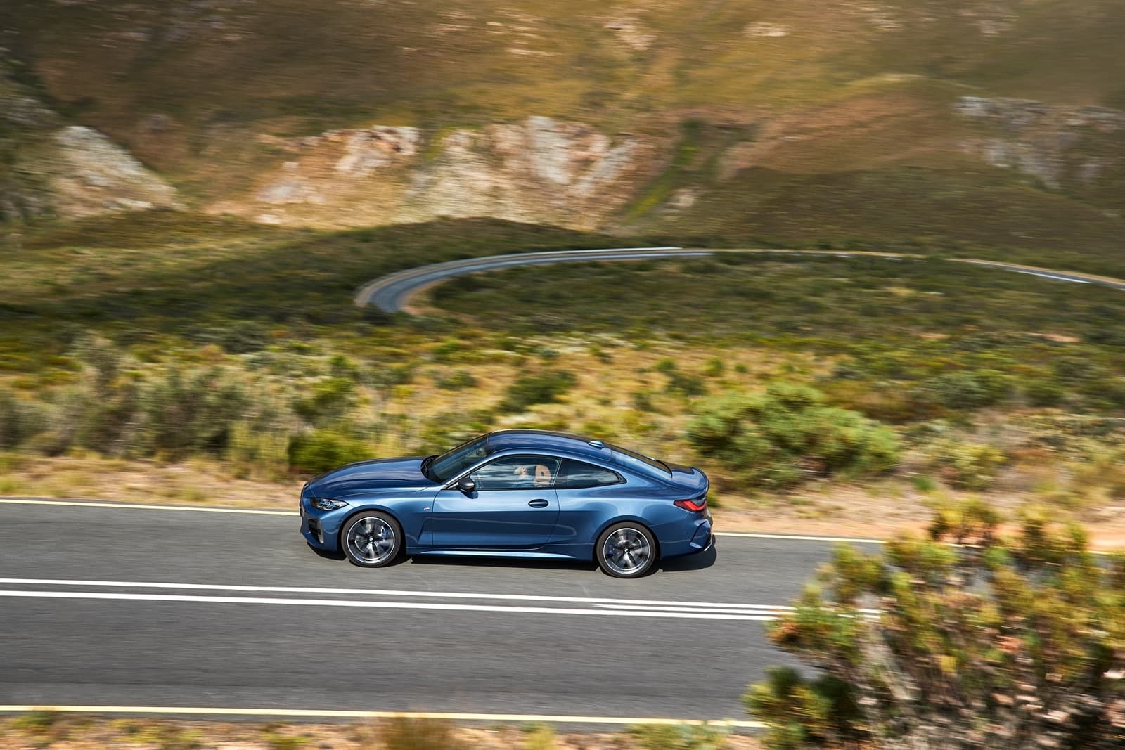 BMW Serie 4 mostrando su perfil lateral en una carretera de montaña.