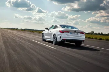 Vista dinámica del BMW Serie 4 en carretera, destacando su diseño trasero y lateral.