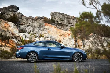 Vista lateral del BMW Serie 4 en un entorno natural con montañas al fondo.