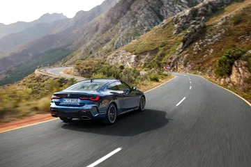 Vista dinámica del BMW Serie 4 en carretera de montaña, énfasis en diseño trasero y lateral.
