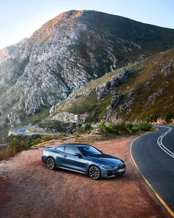 Vista lateral de un BMW Serie 4 en carretera de montaña, realzando su diseño deportivo