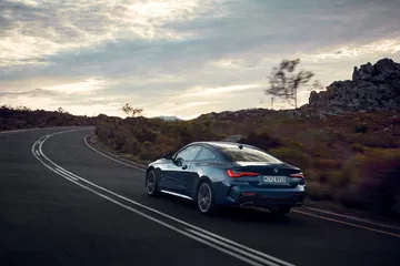 Vista dinámica de un BMW Serie 4 en carretera, mostrando líneas y diseño trasero.