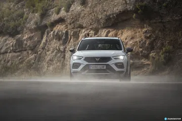 Vista frontal del CUPRA Ateca avanzando con decisión en carretera húmeda.