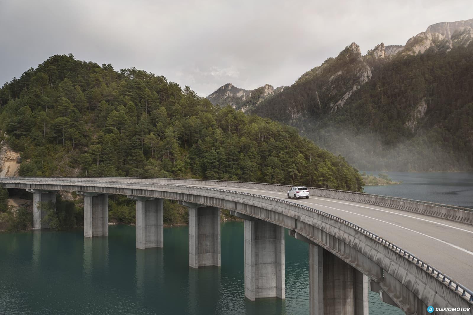 Vista lateral del CUPRA Ateca cruzando un imponente puente en montaña.