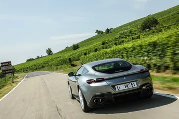 Vista dinámica del Ferrari Roma en carretera, destacando su silueta trasera y lateral.