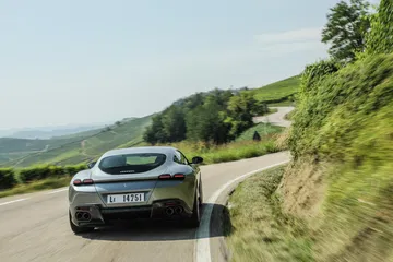 Vista dinámica del Ferrari Roma en carretera, enfatizando su diseño trasero y lateral.