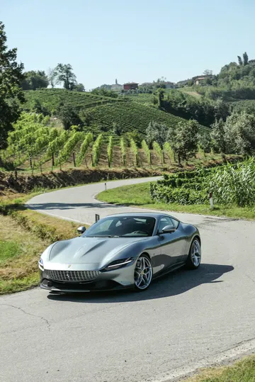 Ferrari Roma en carretera con diseño frontal elegante y perfil dinámico.