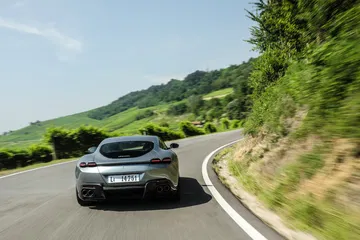 Vista trasera y lateral del Ferrari Roma rodando por una carretera serpenteante