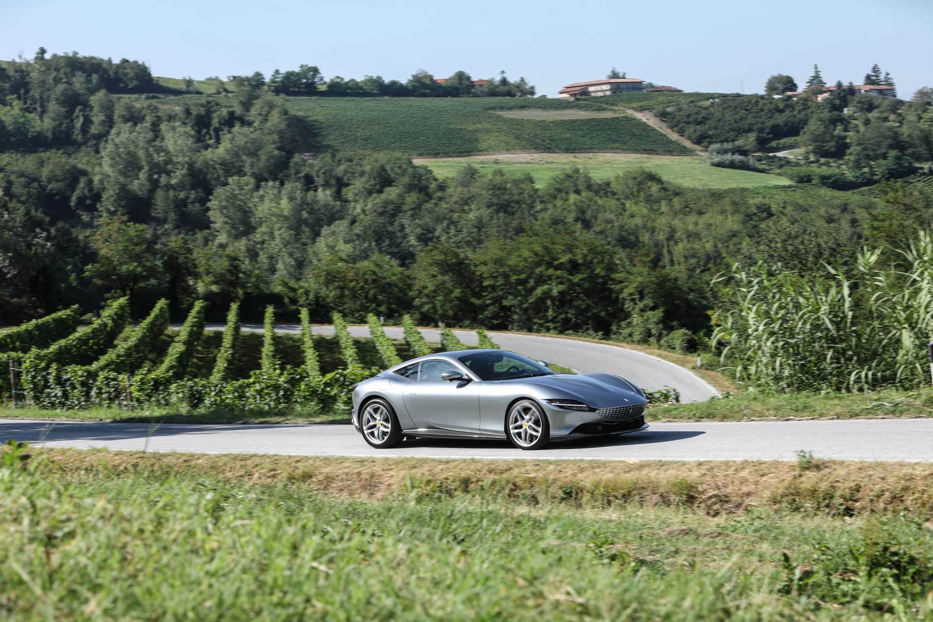 El Ferrari Roma exhibe su elegante silueta lateral en un entorno campestre.
