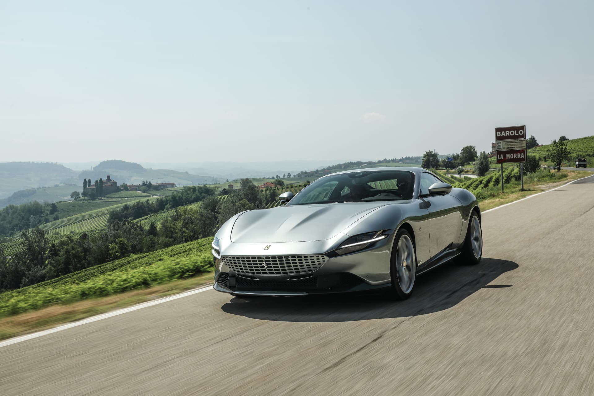 Vista frontal y lateral del Ferrari Roma con un paisaje natural de fondo