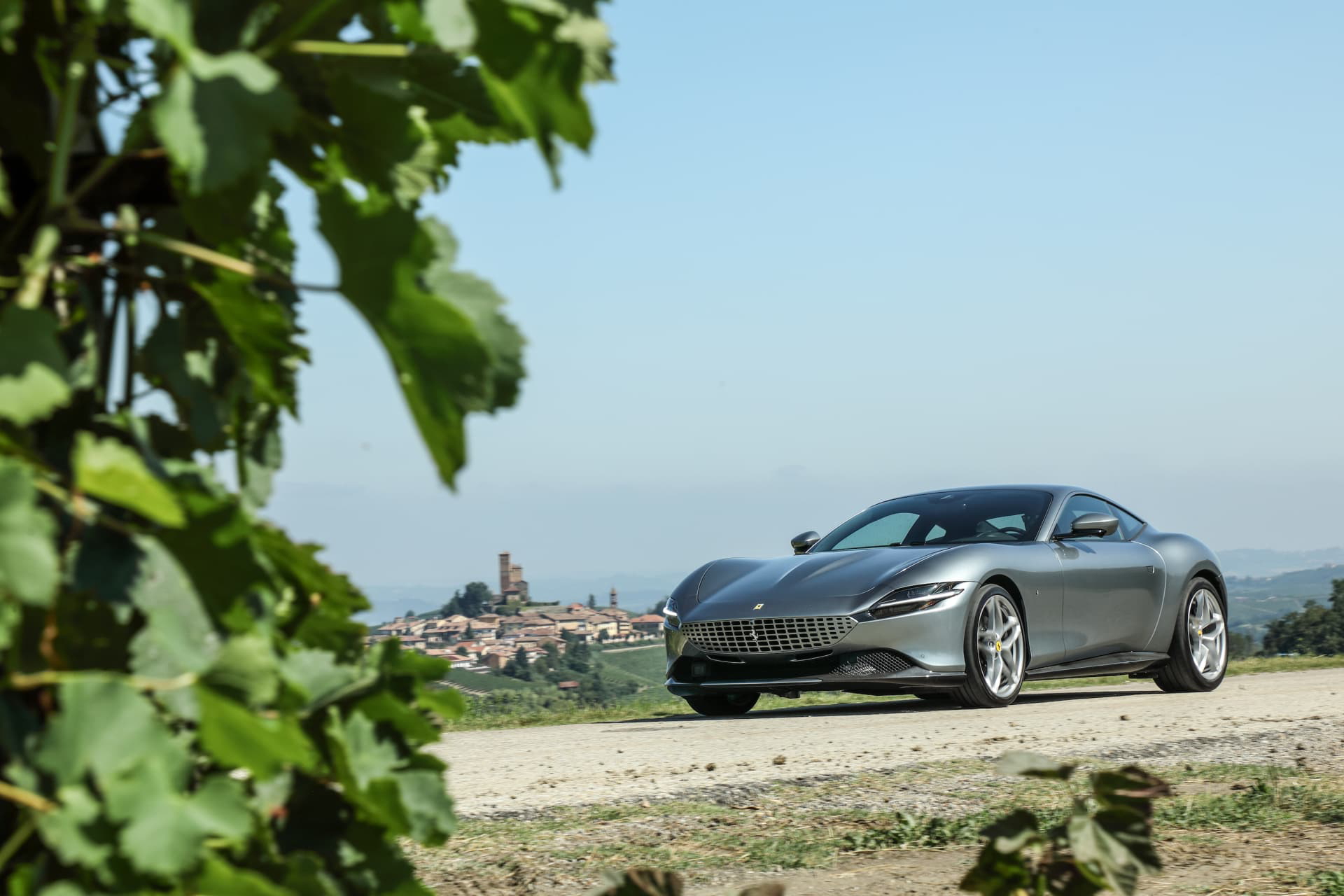 Ferrari Roma captado en perfil lateral con un paisaje campestre al fondo.