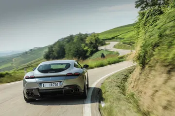 Ferrari Roma mostrando su elegante diseño trasero y lateral en movimiento.