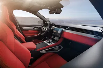 Vista lateral del habitáculo del Jaguar F-PACE, acabados en rojo y negro.