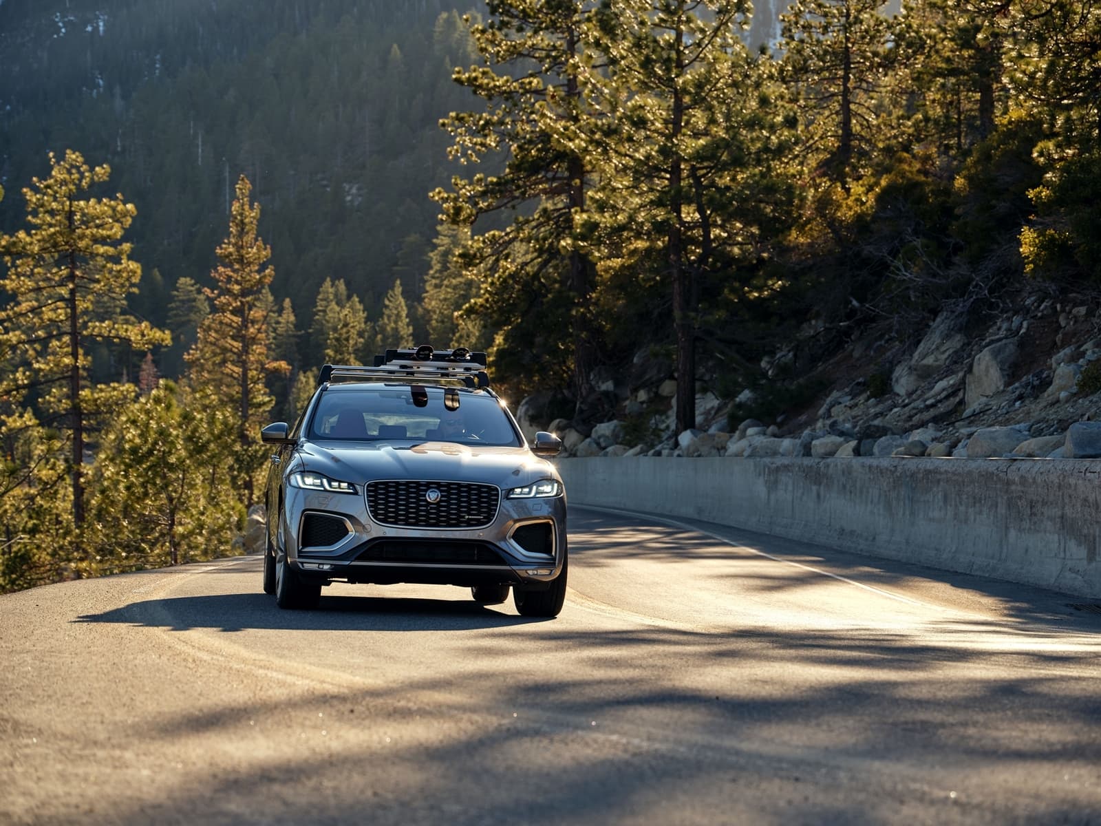 Vista dinámica del Jaguar F-PACE en carretera de montaña, enfatizando su diseño frontal y lateral.