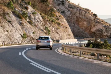 Vista dinámica del Jaguar F-PACE abordando una curva en carretera de montaña.
