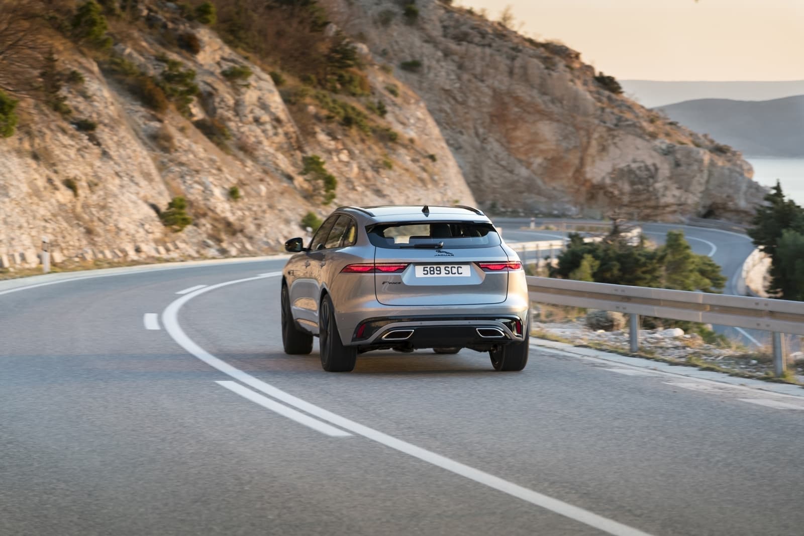 Vista trasera y lateral del Jaguar F-PACE en carretera, destacando su diseño dinámico.