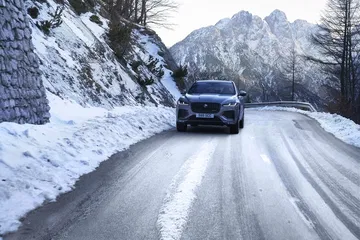 Vista frontal del Jaguar F-PACE en una carretera nevada, destacando su diseño imponente.