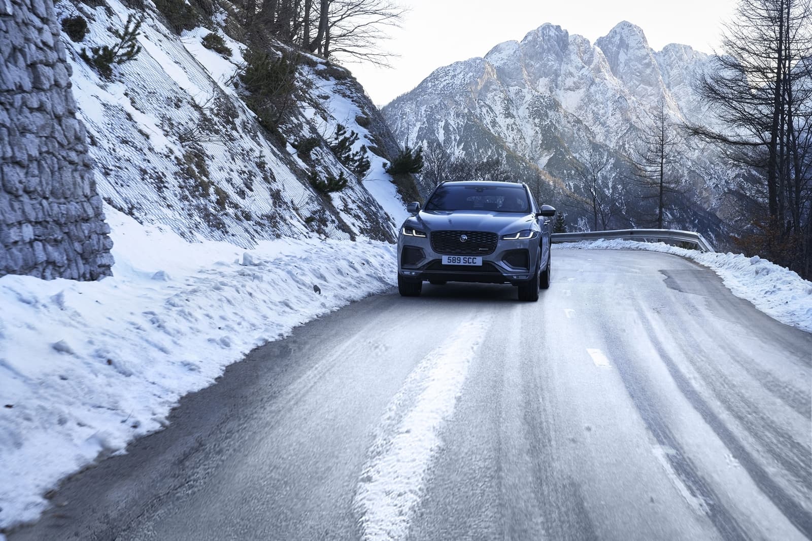Vista frontal del Jaguar F-PACE en una carretera nevada, destacando su diseño imponente.